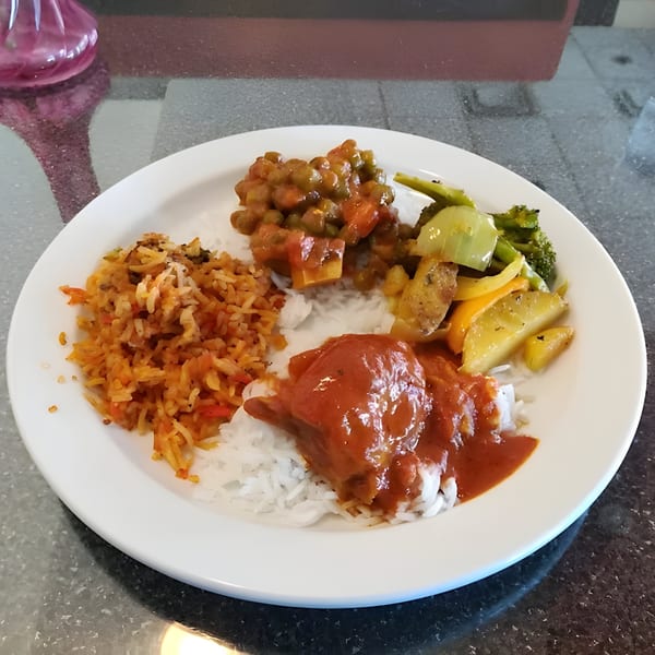 A white plate of Indian food with rice, curry, vegetables, and a pea dish.